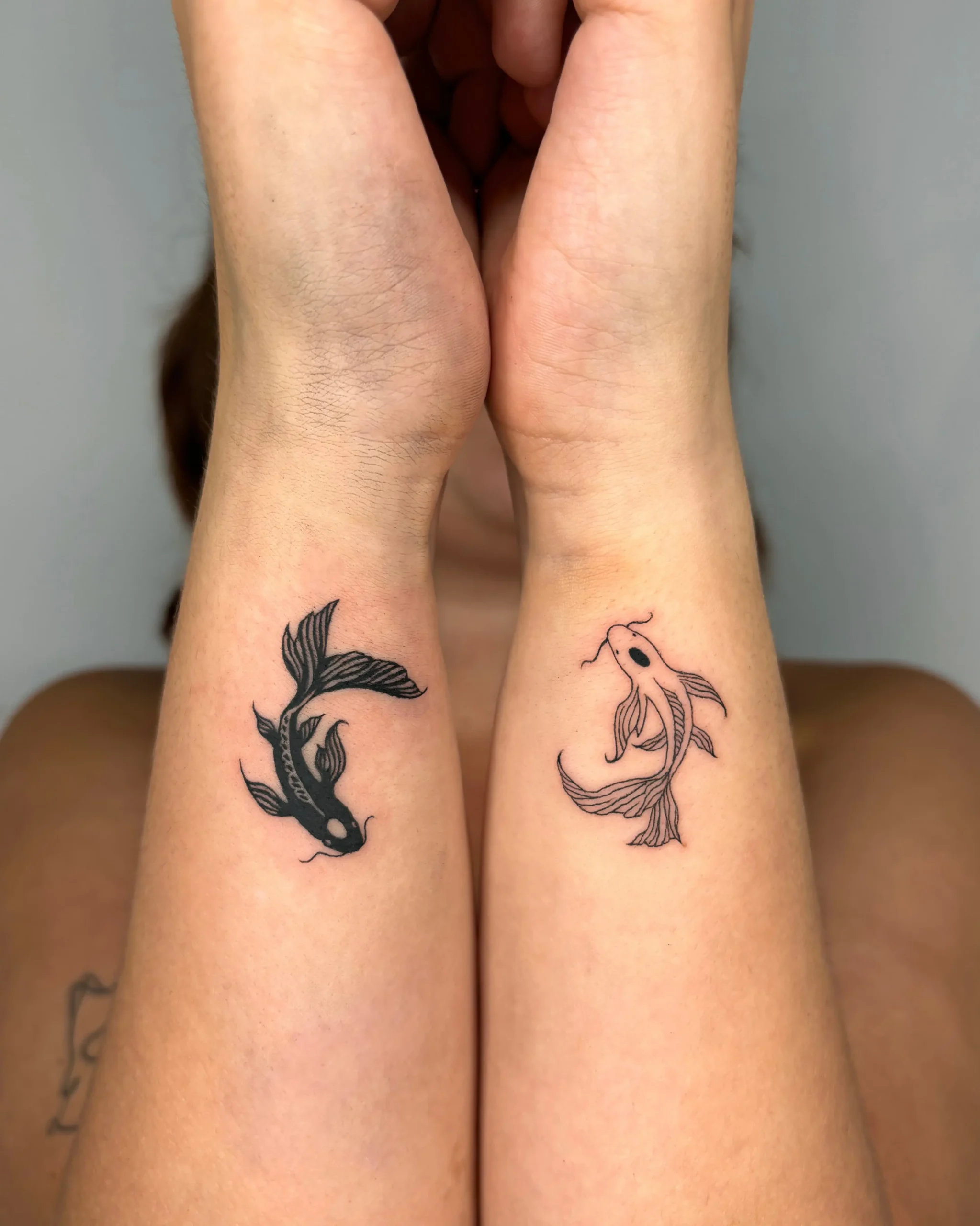 Matching black and grey fine line koi fish tattoos on wrists - Walk In Tattoo Budapest Matching black and grey fine line koi fish tattoos on wrists - Walk In Tattoo Budapest