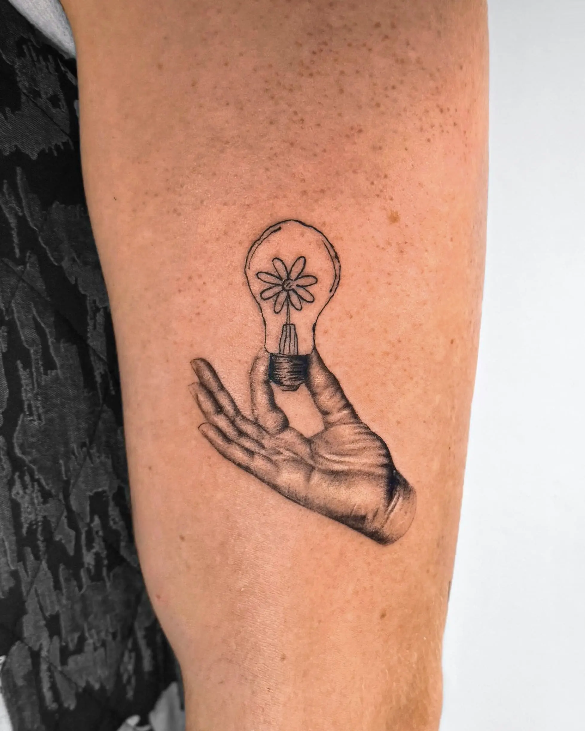 Surrealist tattoo of a hand holding a lightbulb with a flower inside - Walk In Tattoo Budapest