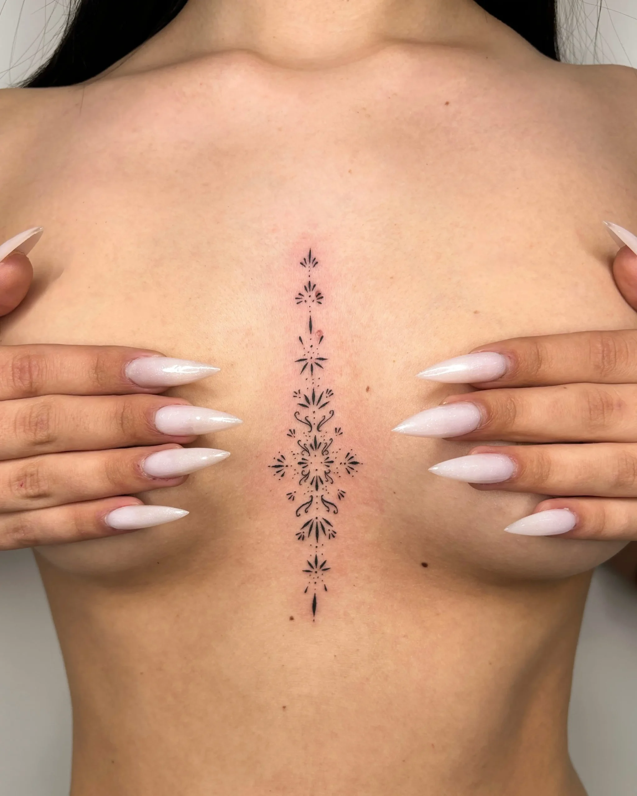 Elegant ornamental sternum tattoo for women, delicate fineline style created at Walk In Tattoo Budapest.