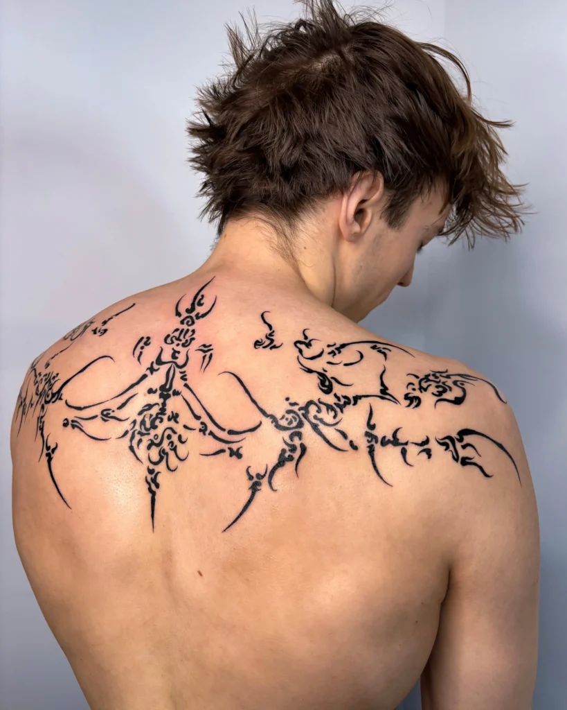 Large ornamental back tattoo with spiritual symbols and bold blackwork flowing across shoulders - Walk In Tattoo Budapest