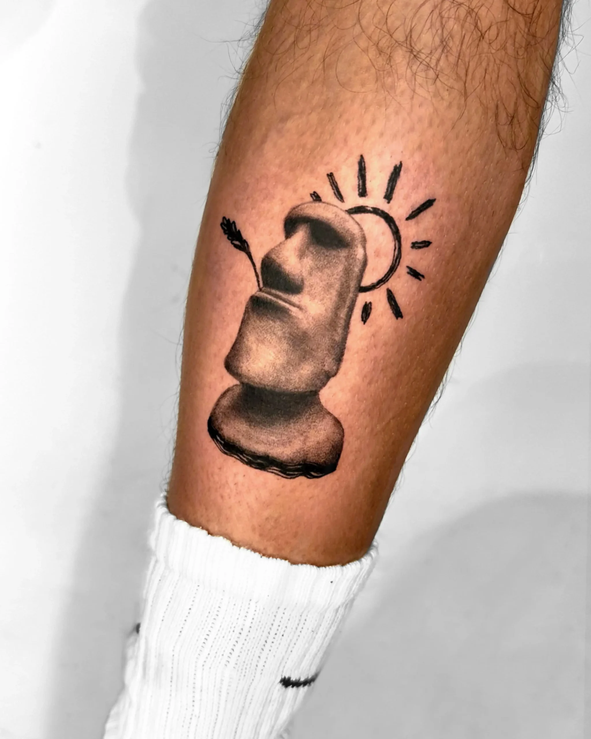 Unique fine line Moai statue tattoo with a sun halo on leg - Walk In Tattoo Budapest